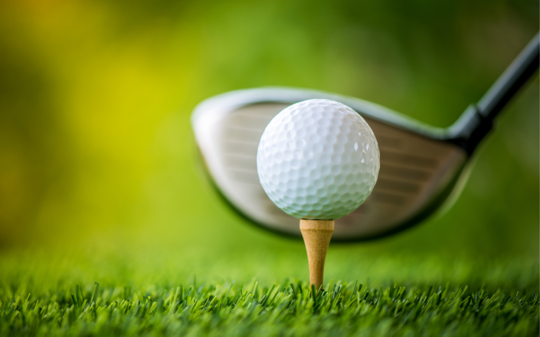 Golf ball on a tee with a putter behind it