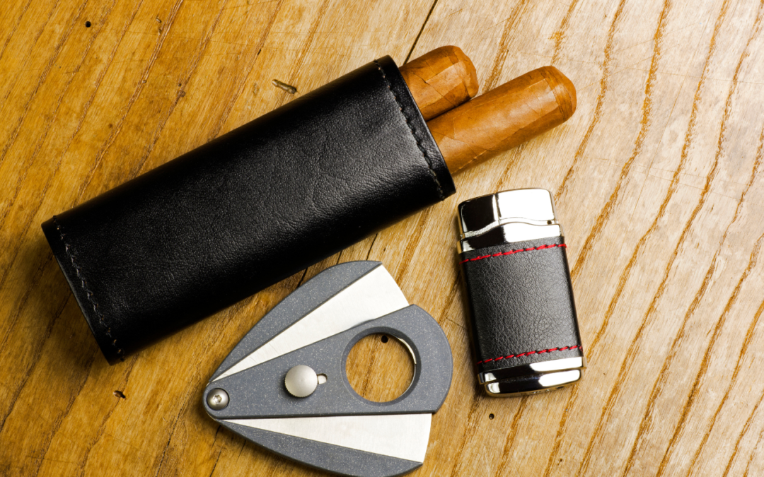 two cigars in a leather holder, a cigar cutter, and a cigar lighter in a leather holder